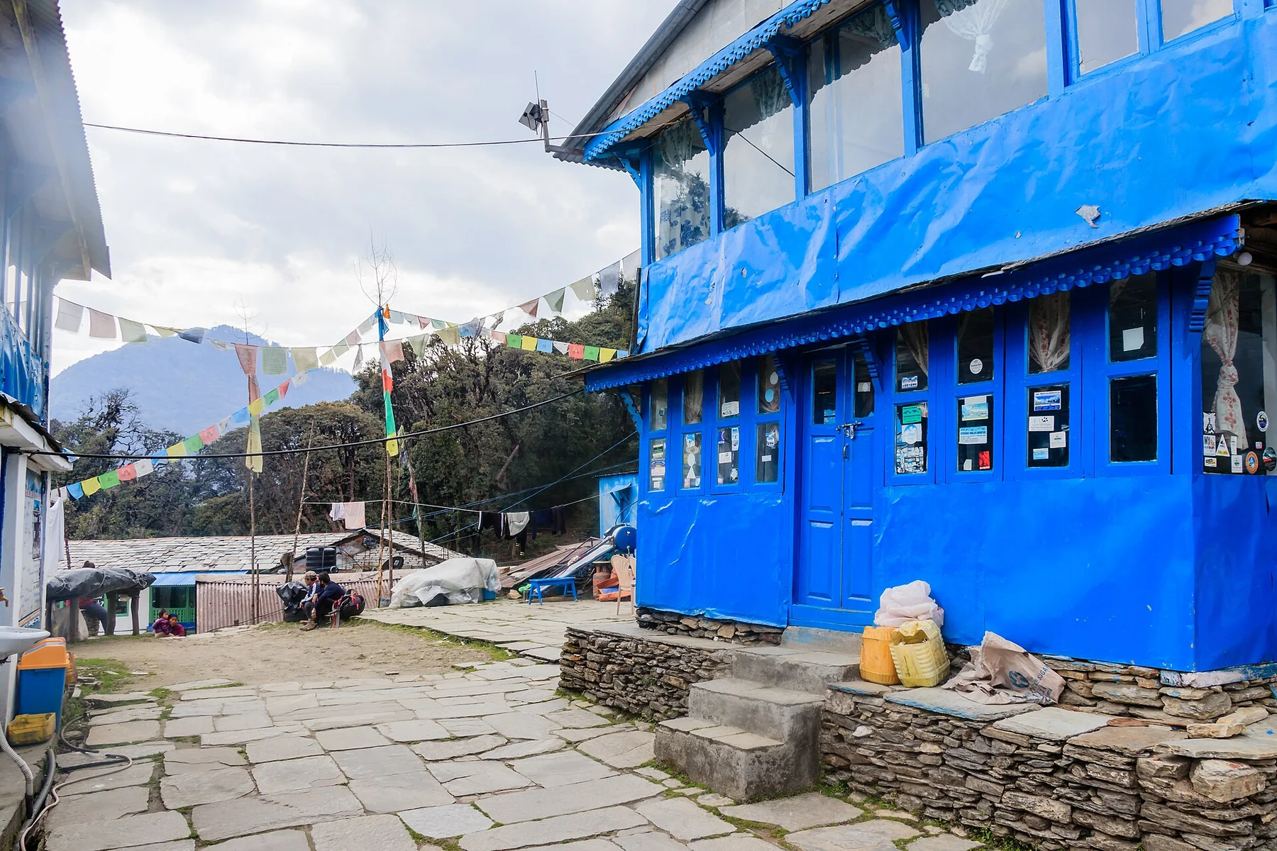 Blue lodge facade and a stone courtyard in Tadapani